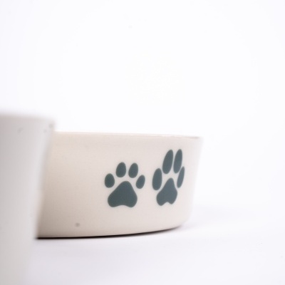 Tigela branca para animais com pegadas de patas verdes
