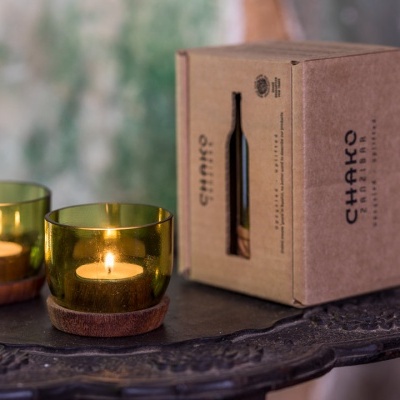Dois castiçais de vidro verde com base em madeira e uma caixa de embalagem castanha com o texto 'CHAKRA'.