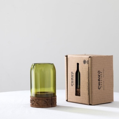 Copo verde reciclado com base de madeira ao lado de caixa castanha com texto