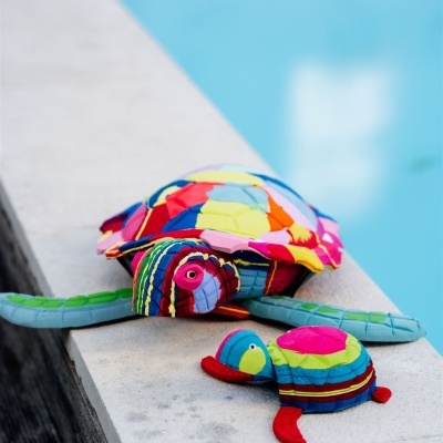 Brinquedos de tecido coloridos em forma de tartaruga ao lado de uma piscina
