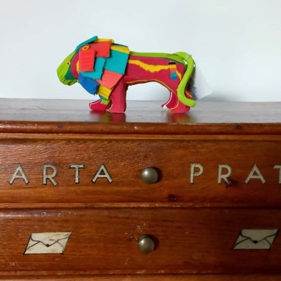 Cómoda de madeira com inscrição 'CARTA PRATA' e figura colorida de touro em cima