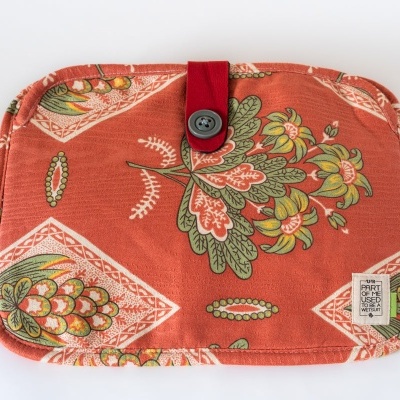 Estojo de tecido vermelho com padrão floral colorido e botão negro.