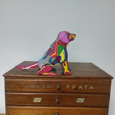 Urso decorativo colorido sobre cómoda de madeira com inscrições CARTA PRATA