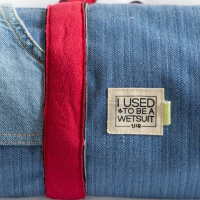 Produto azul tipo ganga com etiqueta e faixa vermelha