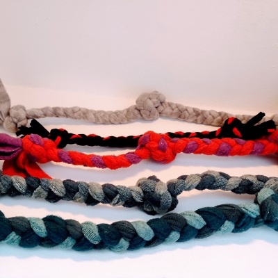 Brinquedos para cães de tecido trançado em três cores diferentes sobre fundo branco