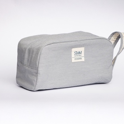 Estojo cinzento riscado com etiqueta SMM e alça de transporte. 