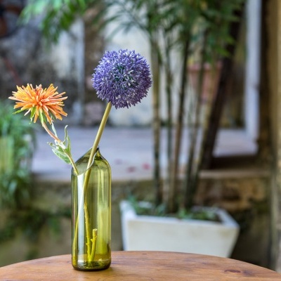 Vaso verde com flores sobre mesa de madeira no exterior