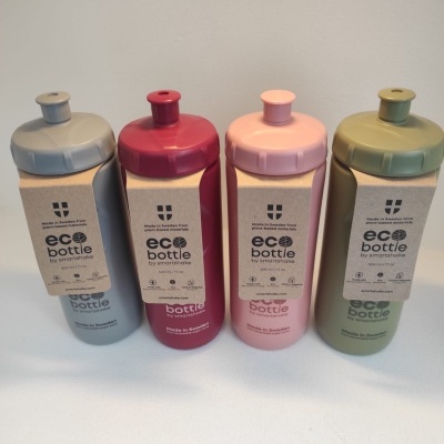 Quatro garrafas eco bottle em cinzento claro, vermelho, rosa e verde com etiquetas de papel reciclado.