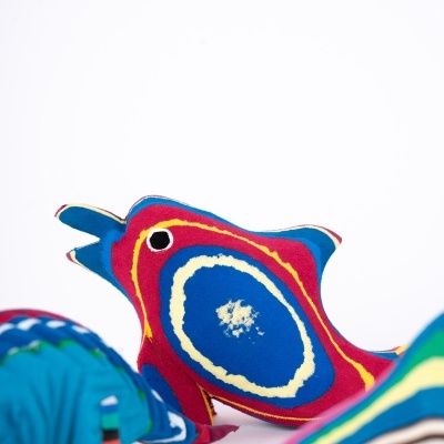 Figuras decorativas em tecido colorido incluindo um peixe vermelho e um elefante azul