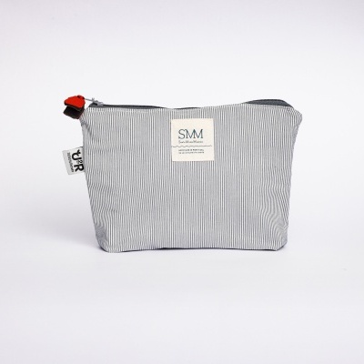 Necessaire cinzenta com padrão listrado e etiquetas visíveis