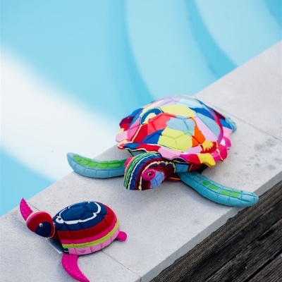 Duas tartarugas de peluche coloridas em patchwork junto a uma piscina