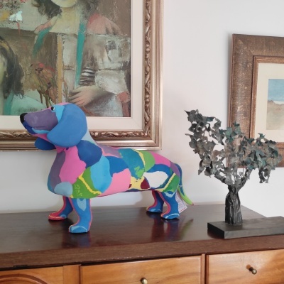 Estátua colorida de cão Dachshund e escultura de árvore sobre móvel de madeira