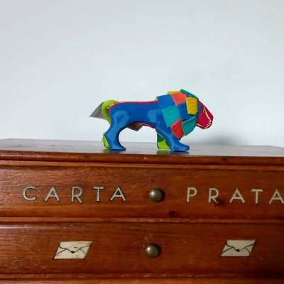 Gaveta de madeira com texto CARTA PRATA e leão multicolorido em tecido em cima