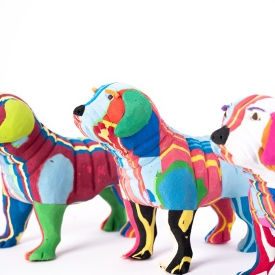 Três bonecos de cães em tecido colorido com padrões abstratos