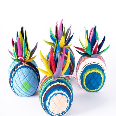 Três abacaxis decorativos de tecido colorido sobre fundo branco