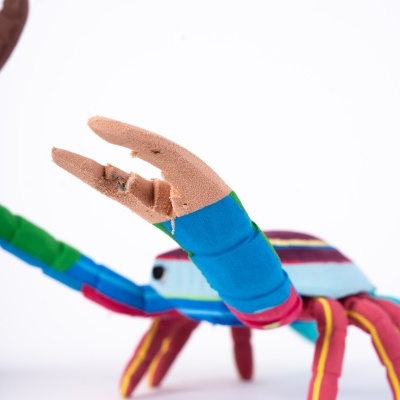 Brinquedo de caranguejo colorido em tecido com riscas sobre fundo branco