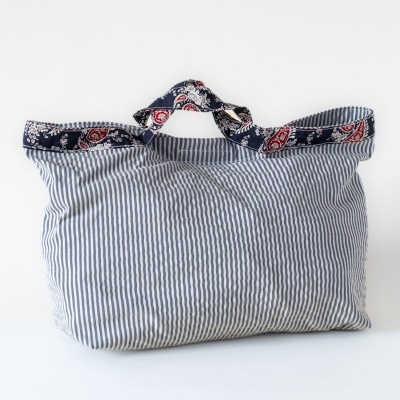 Saco de tecido azul claro com riscas brancas e alças com padrão colorido