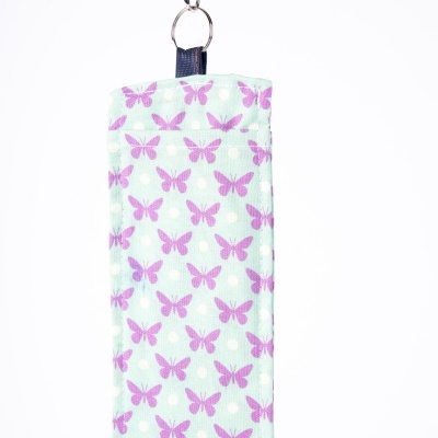 Estojo tecido azul claro com padrão de borboletas roxas e bolinhas brancas e alça verde