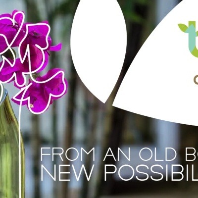 Vaso feito com garrafa de vidro reciclada com flores cor-de-rosa e texto promocional