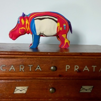 Caixa de madeira com gavetas e figura decorativa de rinoceronte colorido em cima