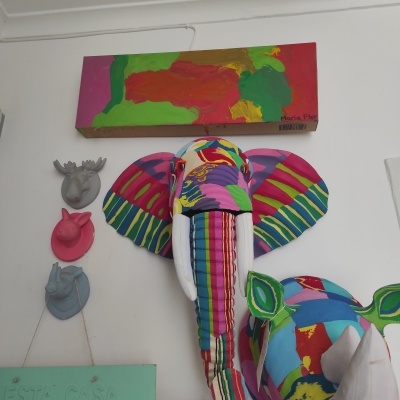 Cabeça de elefante em tecido colorido em parede branca com pintura abstrata e cabeças decorativas de animais