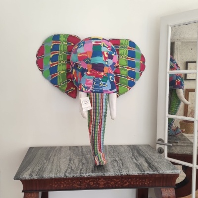 Cabeça decorativa de elefante em tecido colorido montada na parede sobre mesa