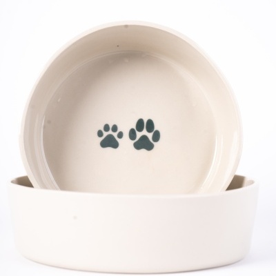 Duas tigelas brancas empilhadas com duas pegadas de patas pretas numa delas