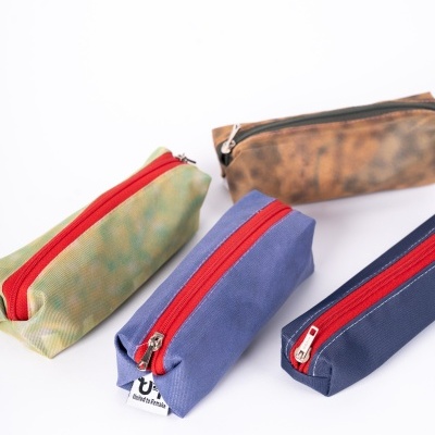 Quatro necessaires retangulares coloridas com fecho zip vermelho sobre fundo branco