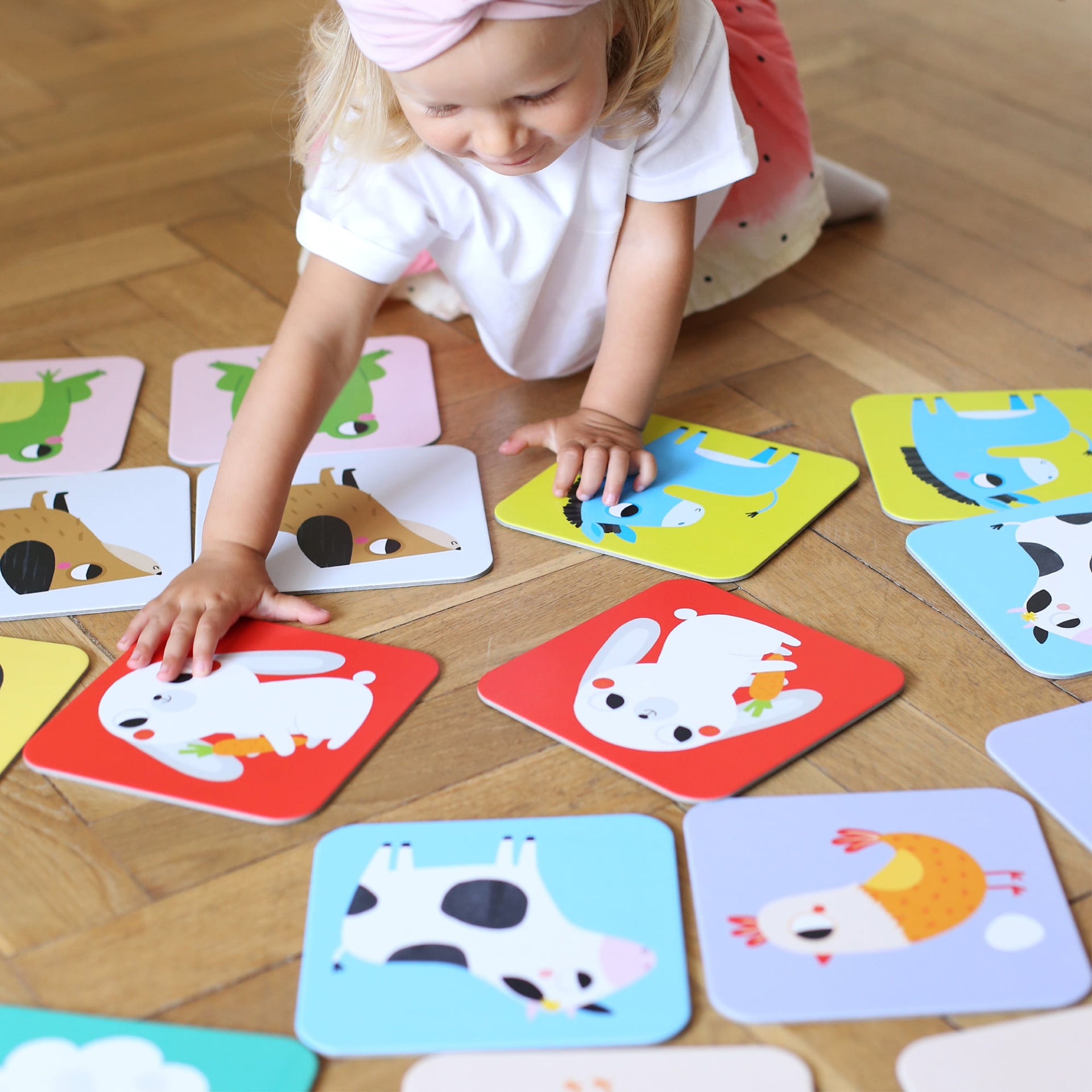 Cartas de animais coloridas para crianças espalhadas no chão de madeira.