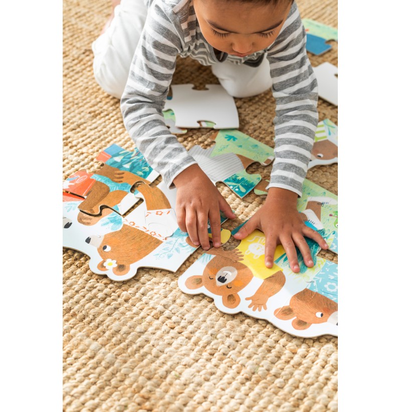Criança a montar puzzle de ursos em cartão sobre tapete bege