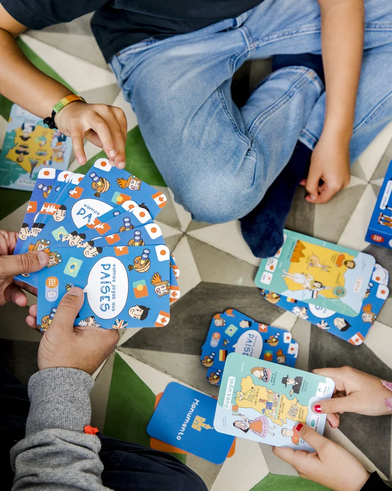 Jogo de cartas coloridas de países e monumentos educativas no chão com crianças jogando.