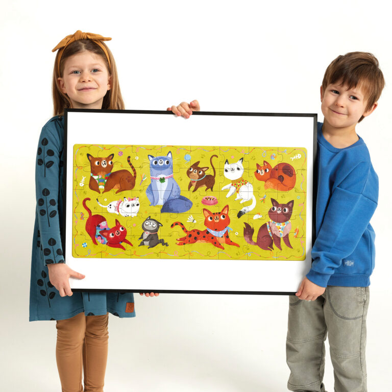 Duas crianças seguram um quadro com ilustração de gatos coloridos em fundo amarelo.