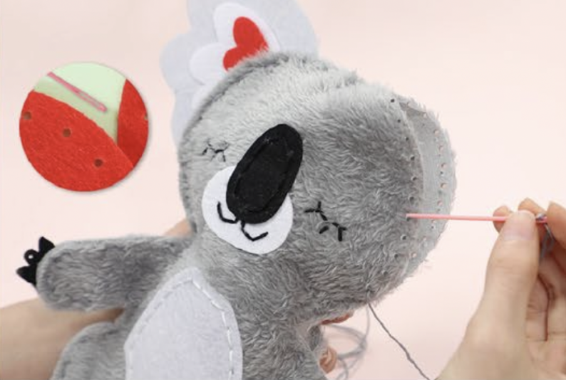 Pelúcia de coala cinzenta a ser costurada com linha cinzenta