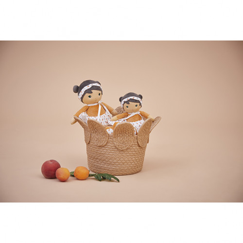 Cesta de palha com duas bonecas de pano e frutas ao lado