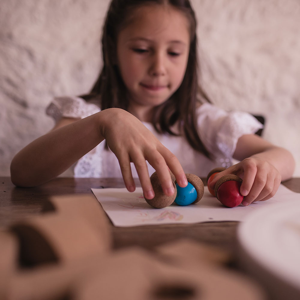 Criança brincando com brinquedos de madeira com bolas azuis e vermelhas sobre mesa de madeira