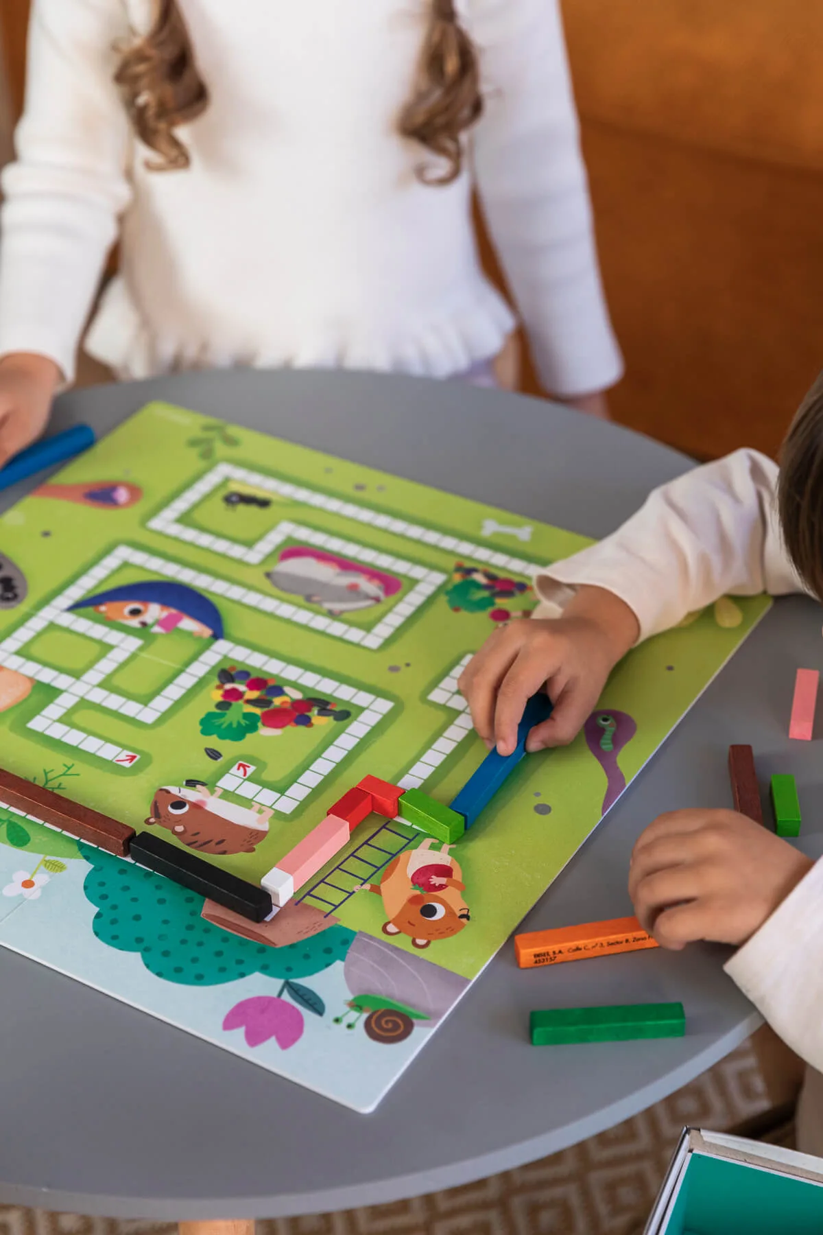 Crianças a jogar jogo de tabuleiro infantil com labirinto e peças de madeira coloridas