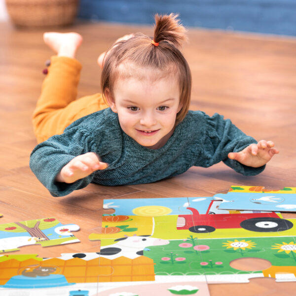 Menino a brincar com puzzle de madeira colorido no chão de madeira