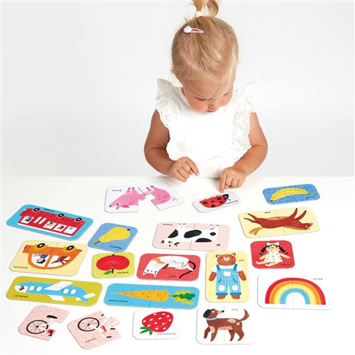 Criança com cartas coloridas de animais e objetos sobre mesa branca