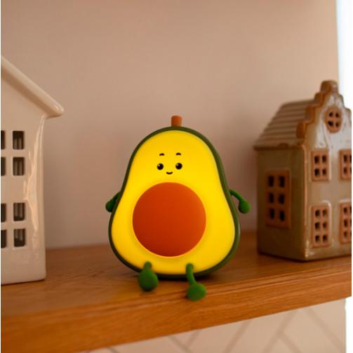 Figura decorativa de abacate com rosto sentado numa prateleira de madeira