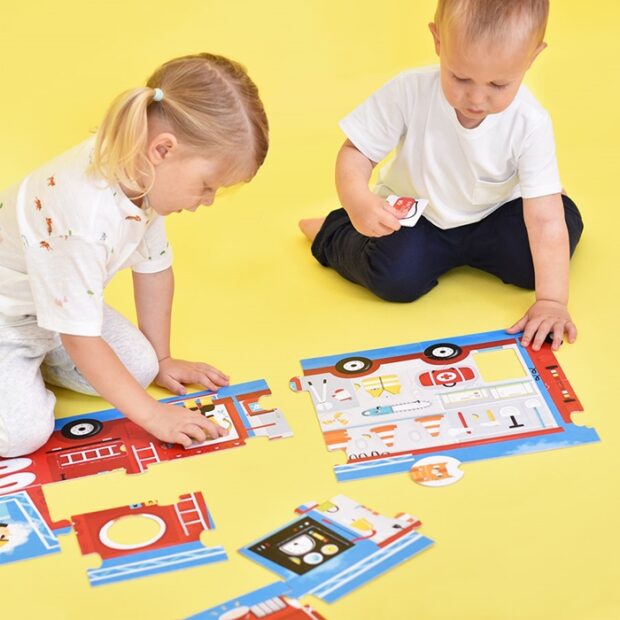 Crianças a montar puzzle infantil de veículos de emergência coloridos sobre fundo amarelo