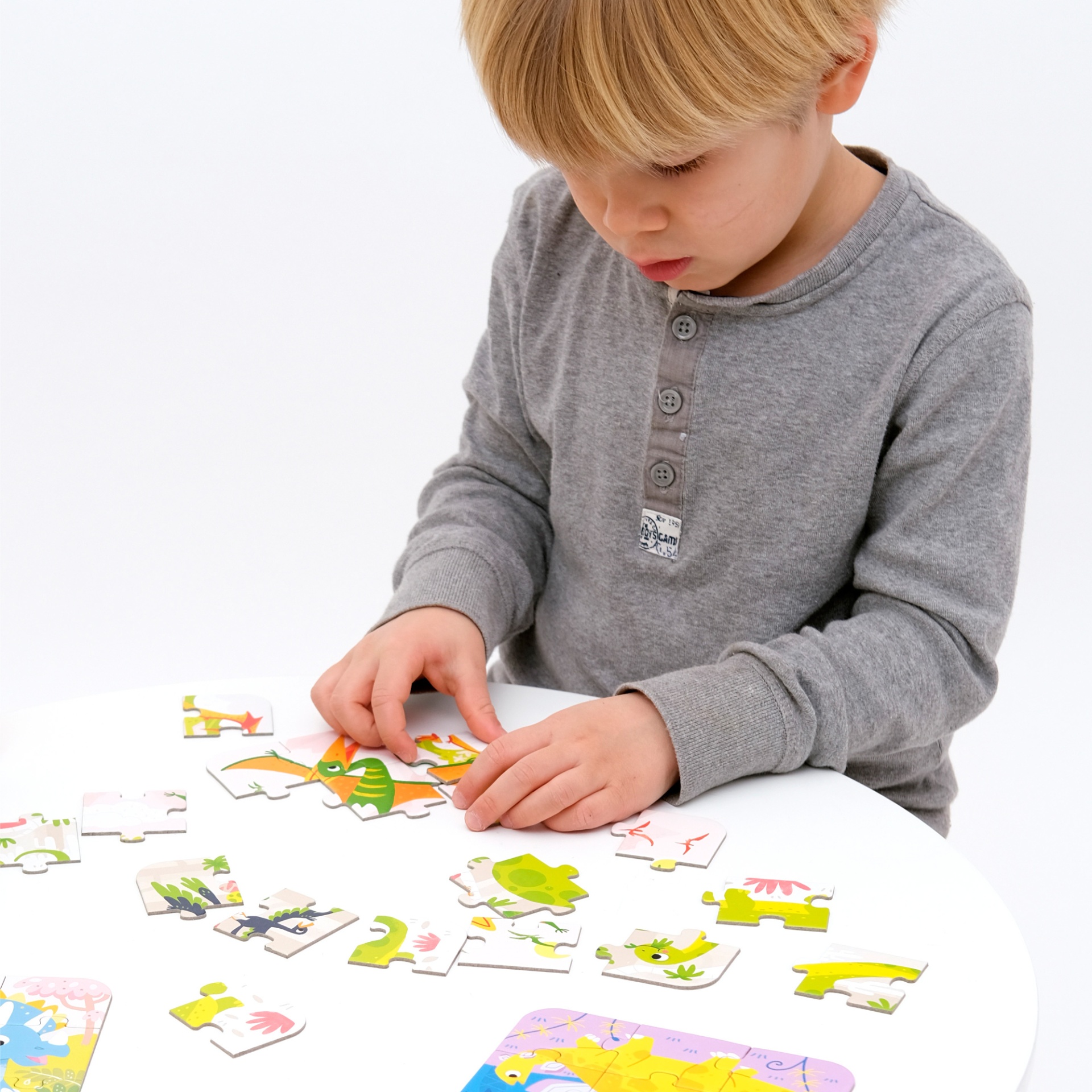 Criança a montar puzzle infantil colorido numa mesa branca