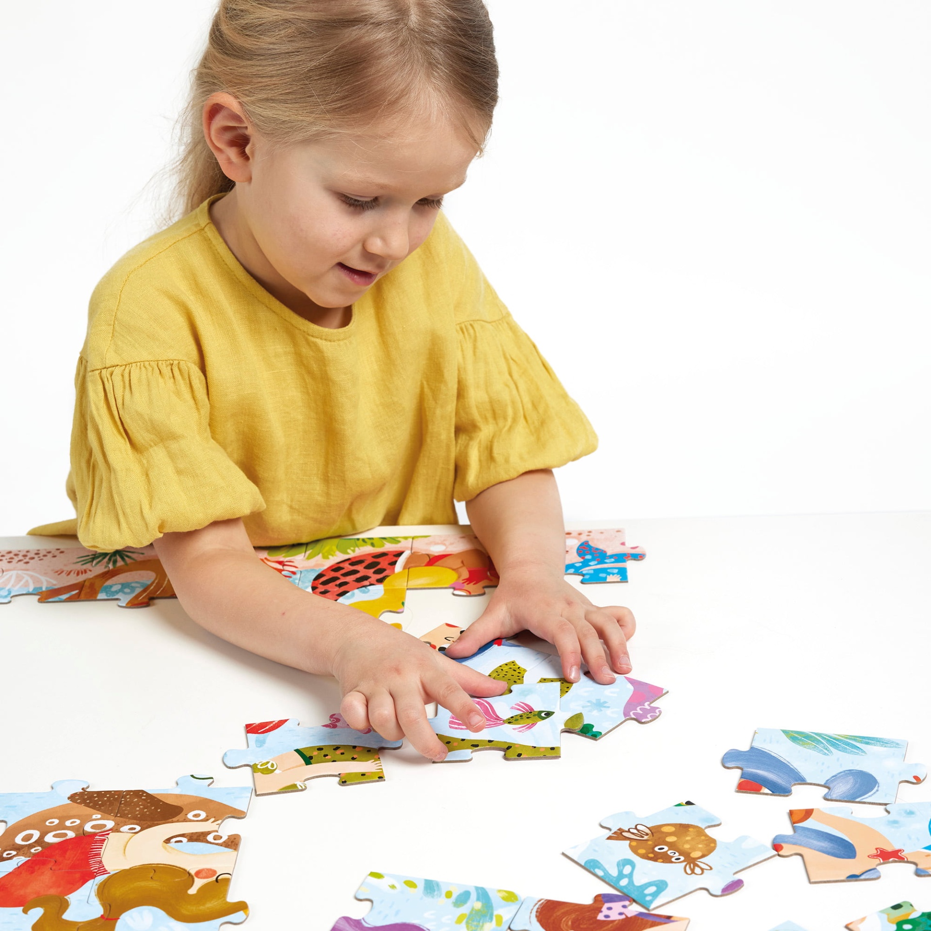 Criança a montar puzzle colorido em mesa branca