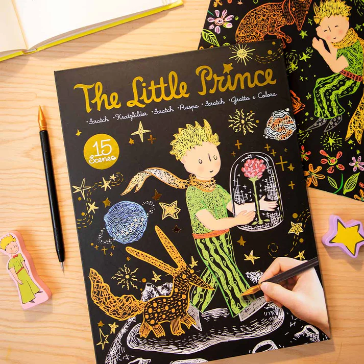 Livro The Little Prince para raspar e colorir com ilustrações coloridas sobre mesa de madeira