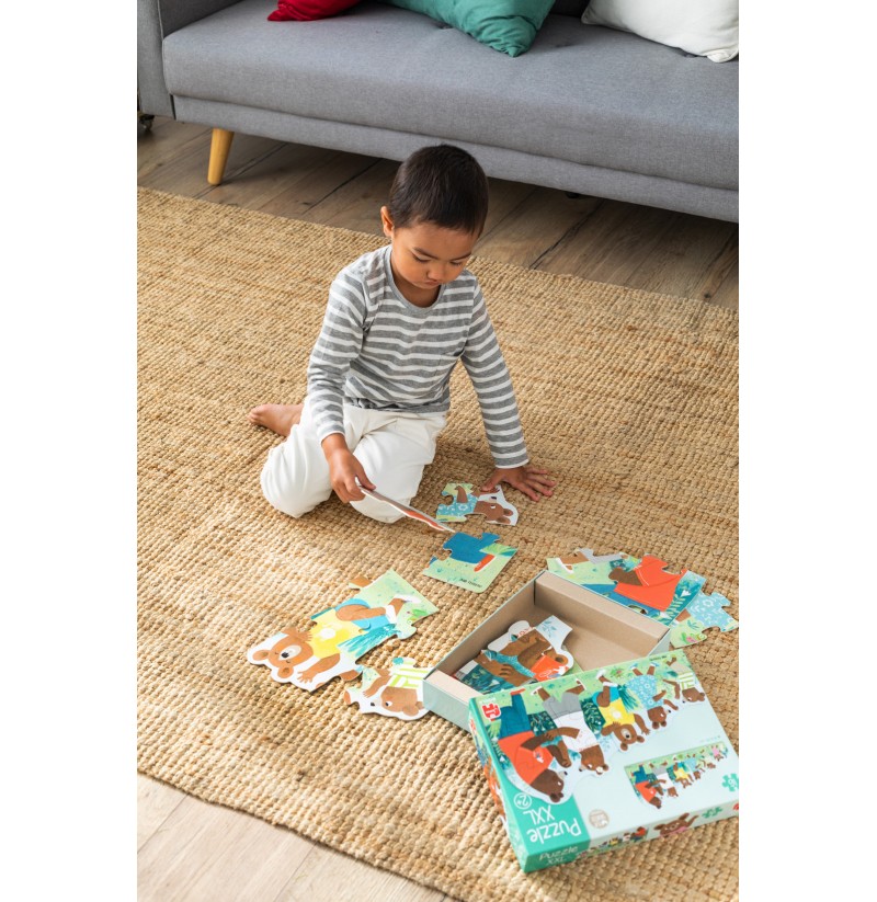 Criança sentado no tapete a montar puzzle de madeira com animais e caixa verde ao lado
