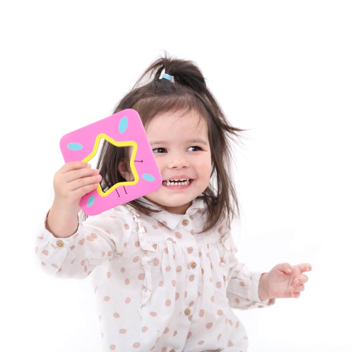 Criança pequena a segurar espelho de mão rosa em forma de estrela