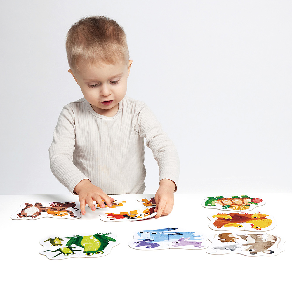 Criança a montar puzzles de madeira com animais coloridos numa superfície branca