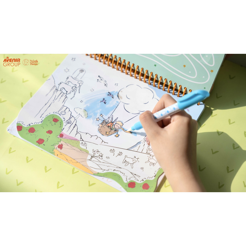Livro para colorir com ilustrações de The Little Prince e caneta azul nas mãos de uma pessoa.