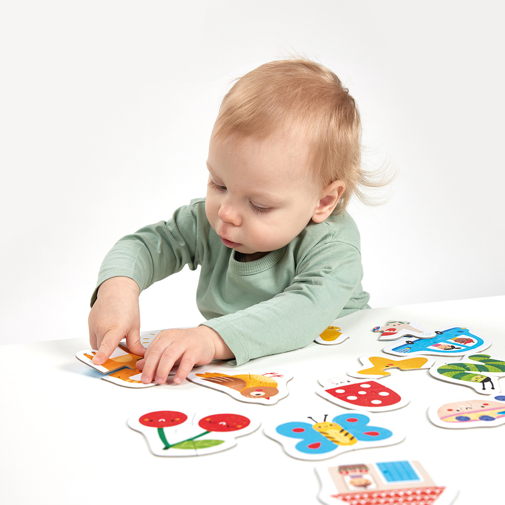 Bebé a montar puzzles coloridos sobre mesa branca