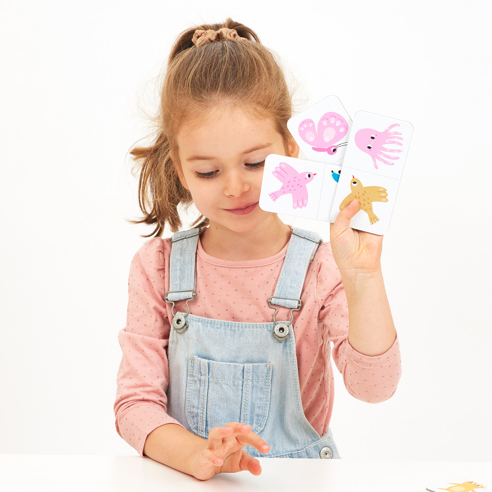 Criança com cartas de jogo coloridas sentada à mesa