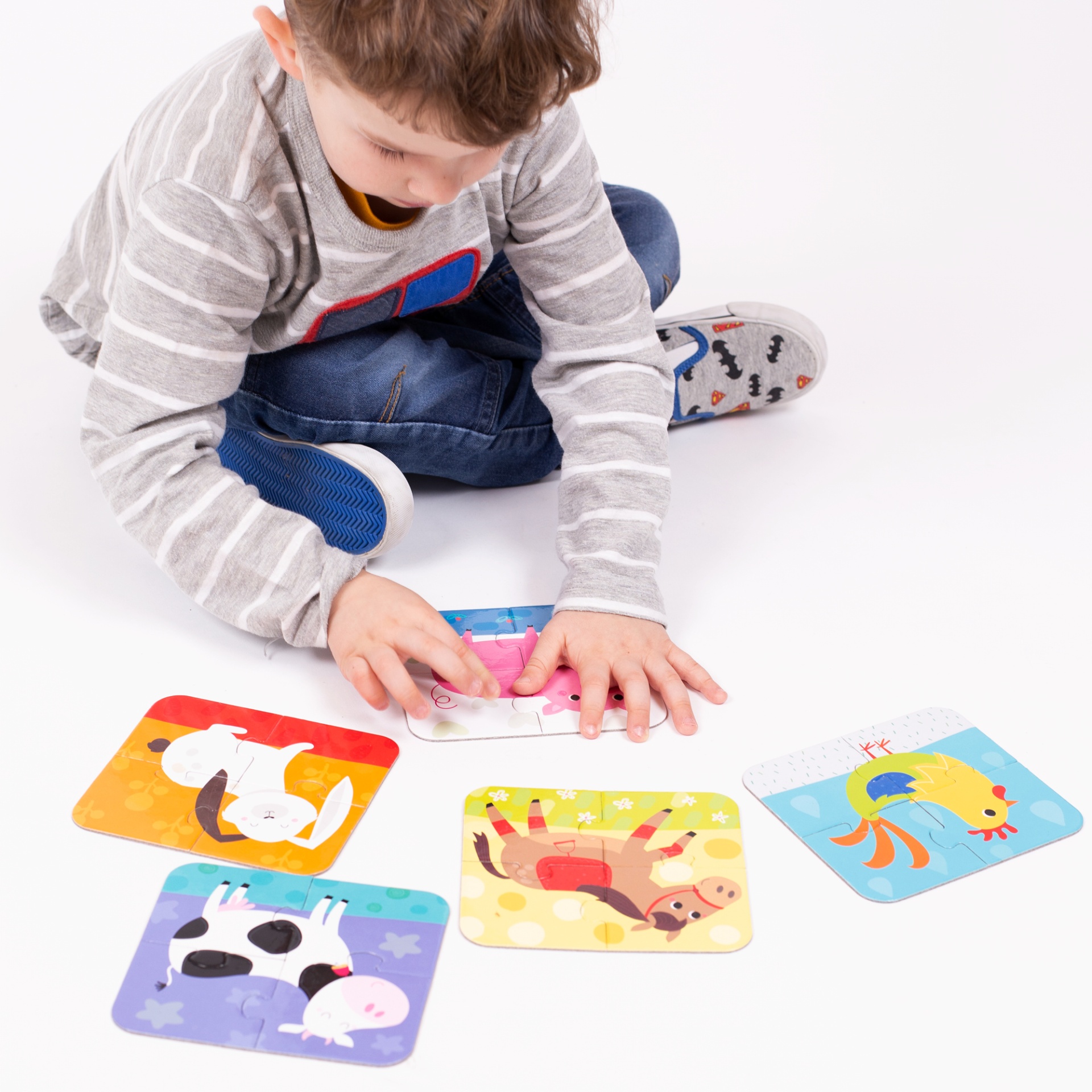 Menino brincando com cartas de animais coloridas em fundo branco